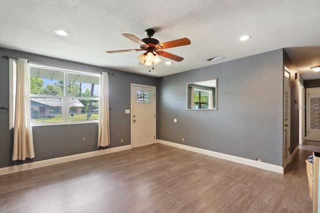 foyer with a textured ceiling, wood finished floors, ceiling fan, and visible vents