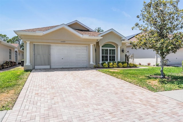 ranch-style home with stucco siding, a front lawn, decorative driveway, and an attached garage