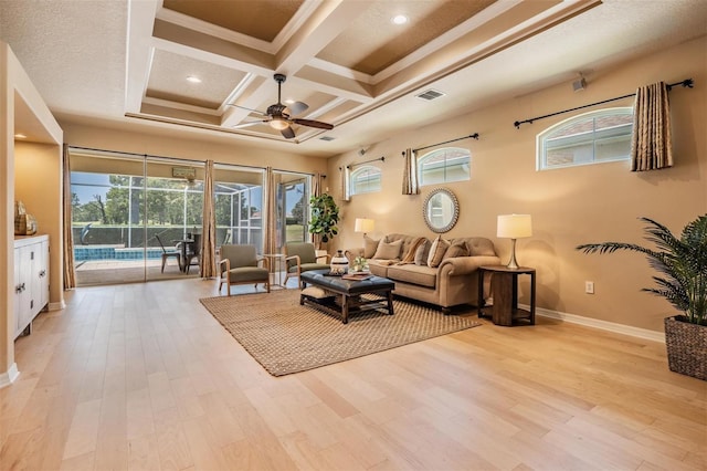 living area with visible vents, baseboards, beam ceiling, light wood finished floors, and a ceiling fan