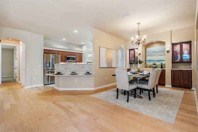 dining area featuring light wood-style flooring, visible vents, arched walkways, an inviting chandelier, and recessed lighting