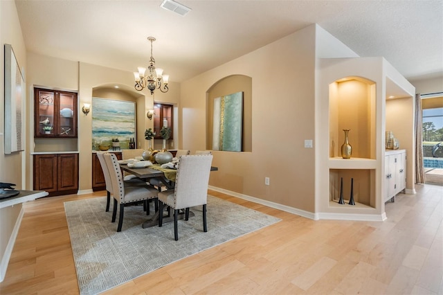 dining area with visible vents, baseboards, a notable chandelier, and light wood-style floors