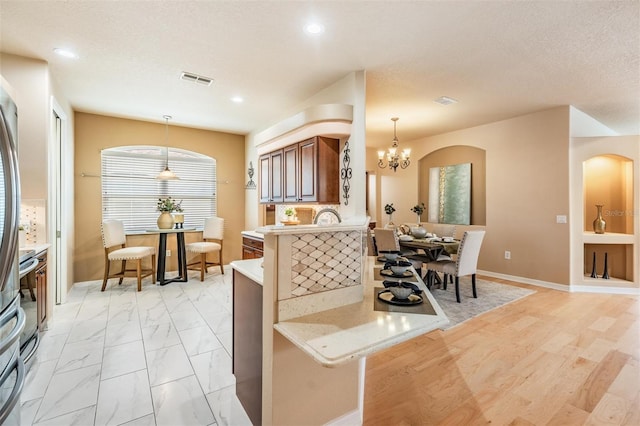 kitchen featuring hanging light fixtures, a notable chandelier, visible vents, and baseboards