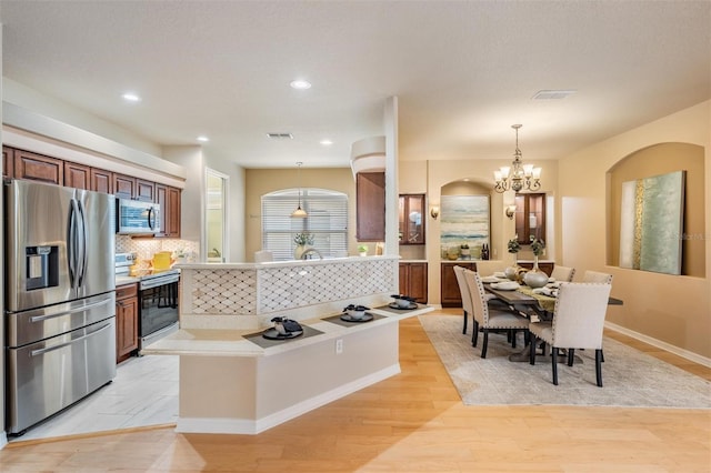 kitchen featuring appliances with stainless steel finishes, light countertops, backsplash, visible vents, and a notable chandelier