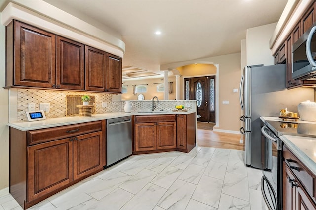 kitchen with a sink, stainless steel appliances, marble finish floor, a peninsula, and ornate columns