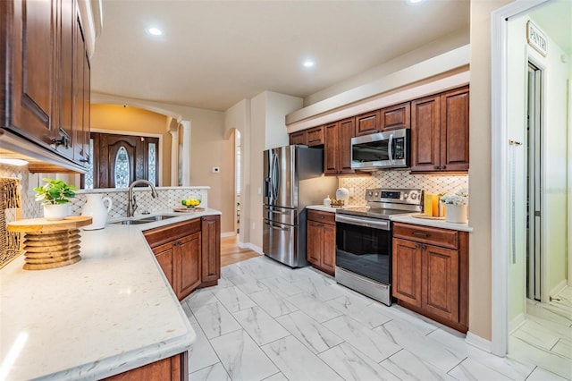 kitchen featuring appliances with stainless steel finishes, a sink, marble finish floor, and arched walkways