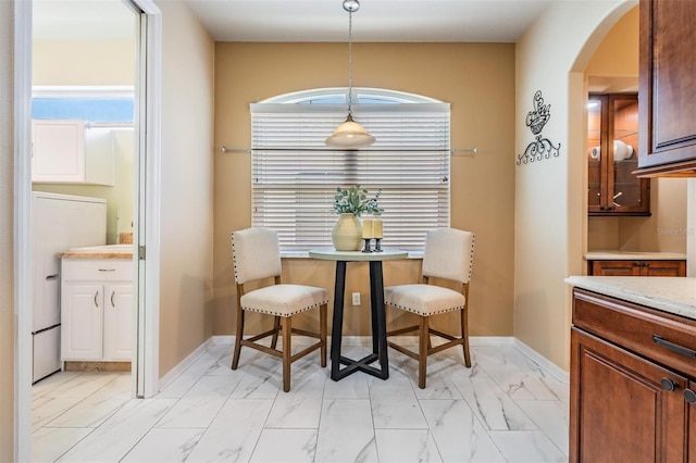 dining room with baseboards, arched walkways, a healthy amount of sunlight, and marble finish floor
