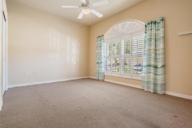 carpeted spare room with a ceiling fan and baseboards