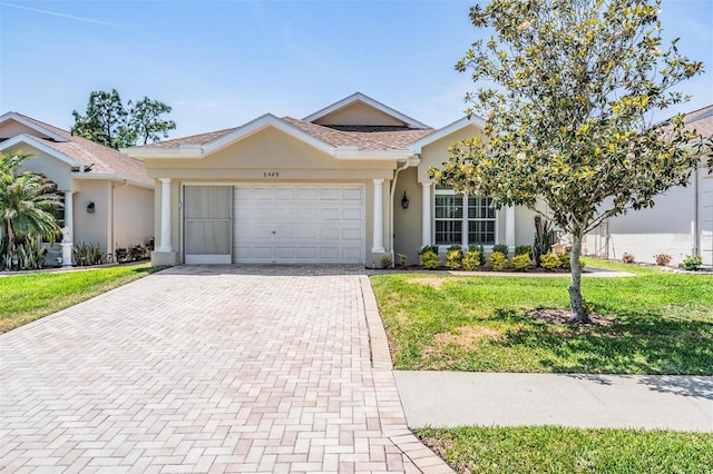 single story home with stucco siding, decorative driveway, a front lawn, and an attached garage