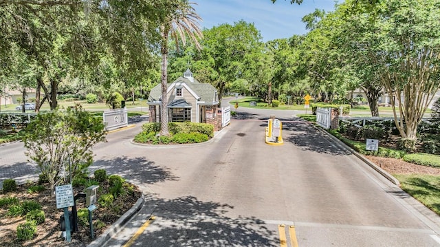 view of road featuring traffic signs, curbs, and a gated entry