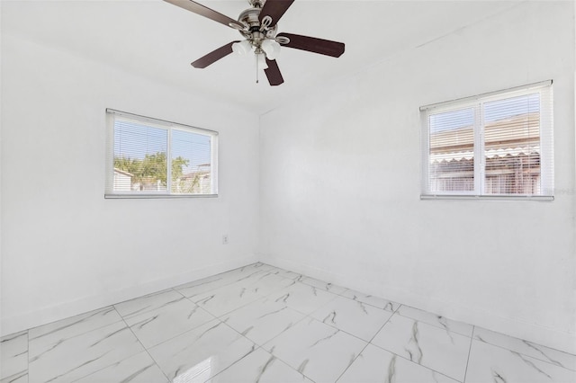 empty room featuring a wealth of natural light, marble finish floor, and baseboards