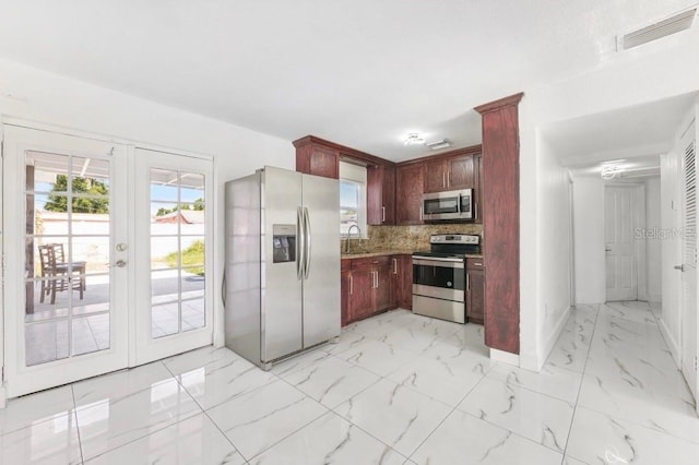 kitchen featuring a sink, visible vents, stainless steel appliances, reddish brown cabinets, and french doors