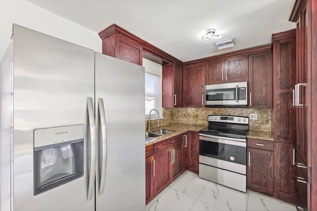 kitchen with tasteful backsplash, light stone countertops, stainless steel appliances, marble finish floor, and a sink