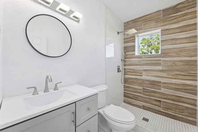 bathroom featuring toilet, tiled shower, and vanity