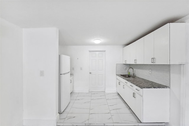 kitchen with marble finish floor, a sink, freestanding refrigerator, and white cabinetry