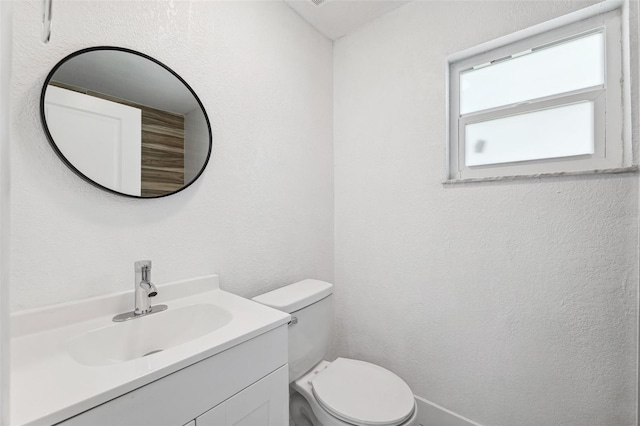 bathroom featuring vanity, toilet, and a textured wall