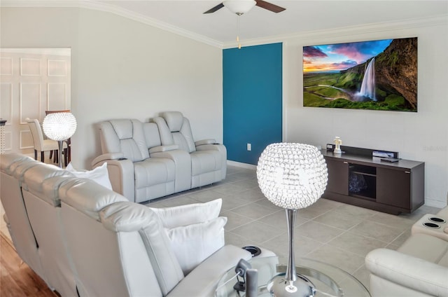 living area featuring light tile patterned flooring, ceiling fan, ornamental molding, and baseboards