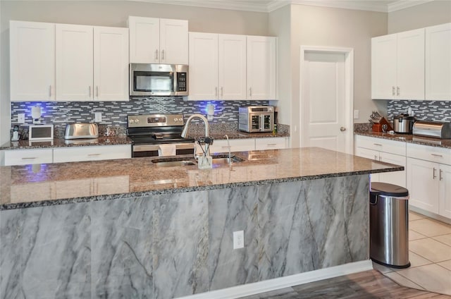 kitchen featuring stainless steel appliances, ornamental molding, a sink, and tasteful backsplash