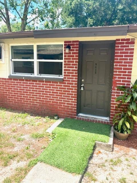 entrance to property featuring brick siding