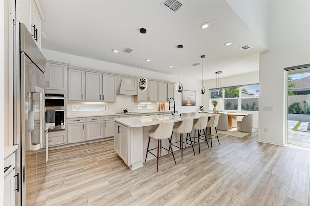 13071 Willow Grove Dr, Riverview, FL 33579 - kitchen with light wood-style floors, appliances with stainless steel finishes, visible vents, and custom range hood