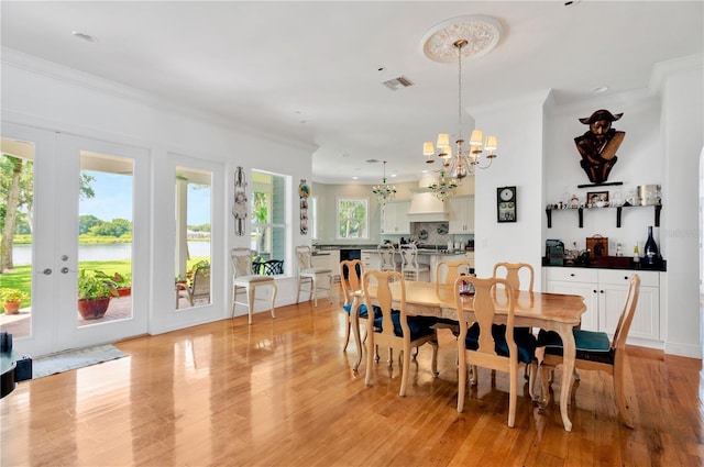 16470 Oakview Cir, Alva, FL 33920 - dining space featuring crown molding, a chandelier, visible vents, a water view, and light wood finished floors