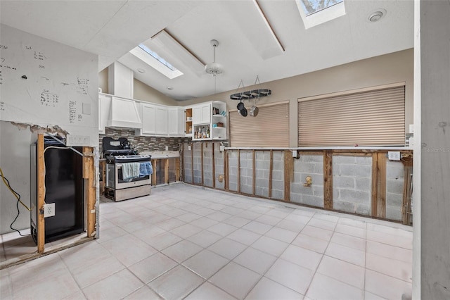 7247 Oelsner St, New Port Richey, FL 34652 - kitchen with lofted ceiling with skylight, open shelves, white cabinets, stainless steel range with gas cooktop, and tasteful backsplash