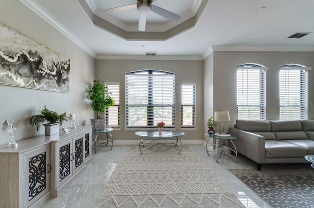 living area with a raised ceiling, ornamental molding, a ceiling fan, and visible vents
