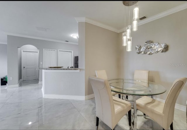 dining area featuring baseboards, ornamental molding, and arched walkways