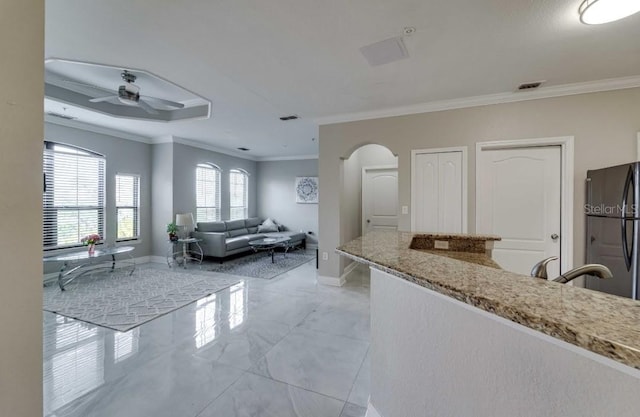 living room with visible vents, ornamental molding, baseboards, ceiling fan, and arched walkways
