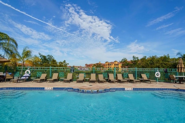 community pool with fence and a patio area
