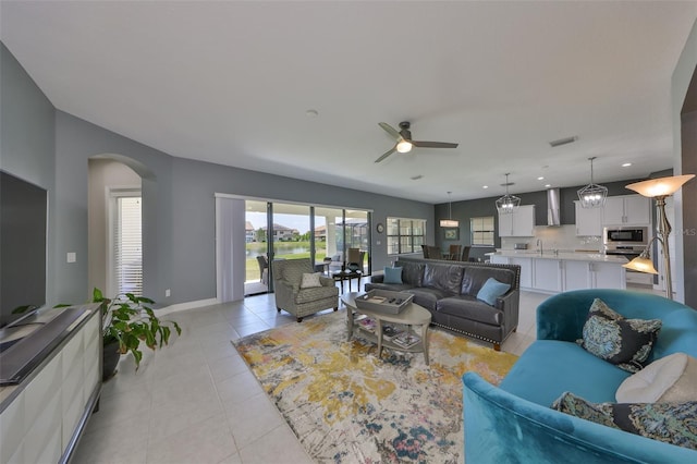 11909 Climbing Fern Ave, Riverview, FL 33579 - living room with light tile patterned floors, ceiling fan, visible vents, baseboards, and arched walkways