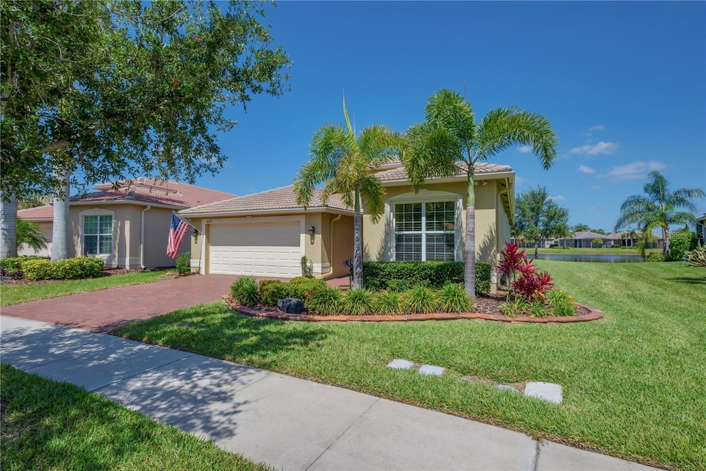 view of front of property with decorative driveway, an attached garage, a front yard, and stucco siding