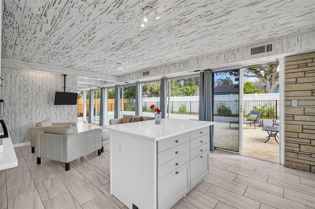 307 Orangewood Ln, Largo, FL 33770 - kitchen with visible vents, a kitchen island, open floor plan, light countertops, and white cabinetry