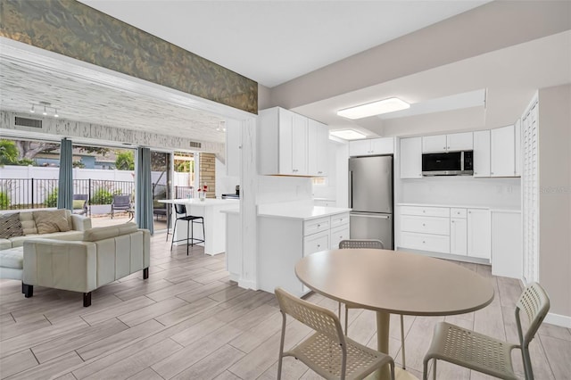 307 Orangewood Ln, Largo, FL 33770 - kitchen featuring white cabinets, appliances with stainless steel finishes, light countertops, open floor plan, and light wood-type flooring
