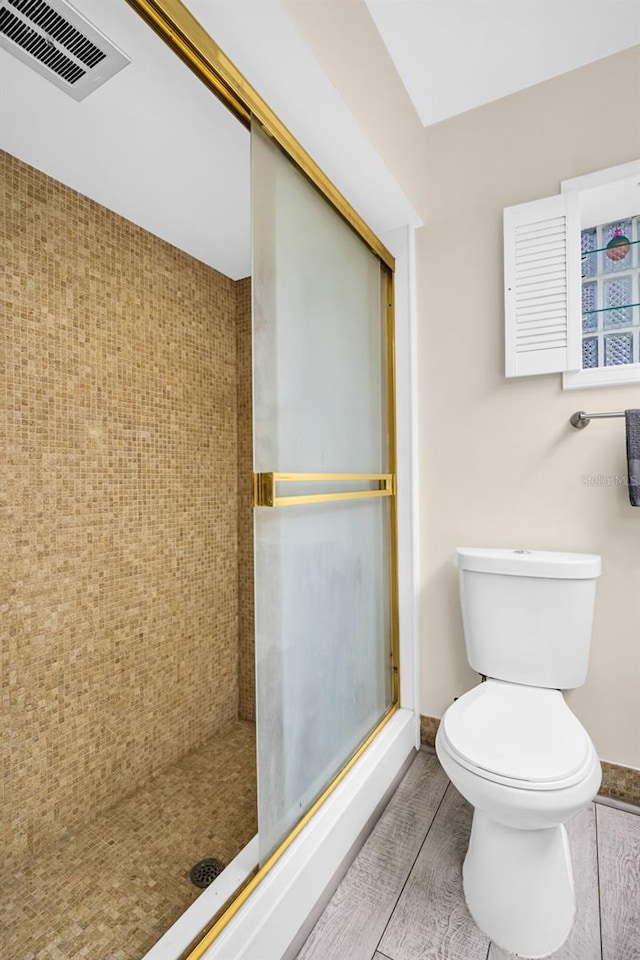 307 Orangewood Ln, Largo, FL 33770 - bathroom with toilet, baseboards, a shower stall, wood finished floors, and visible vents