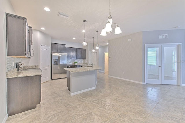 kitchen featuring backsplash, visible vents, appliances with stainless steel finishes, a sink, and an inviting chandelier