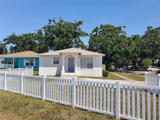 bungalow-style home featuring fence private yard, a shingled roof, and stucco siding