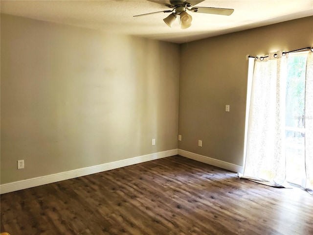 empty room featuring a ceiling fan, baseboards, and dark wood finished floors