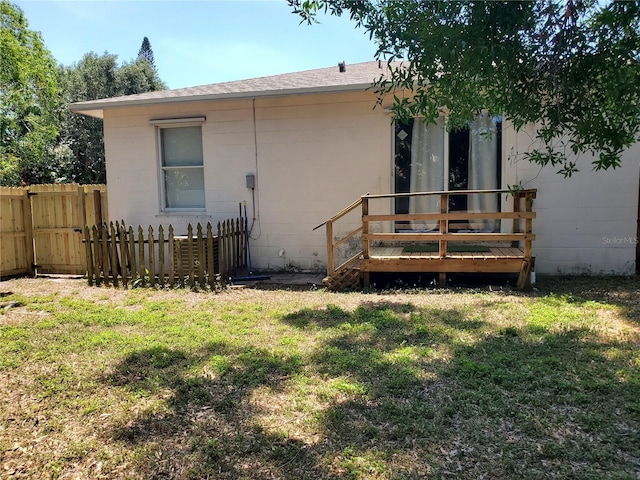 exterior space featuring fence, concrete block siding, and a lawn