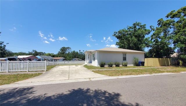 view of front of house with a front yard, driveway, stucco siding, and fence