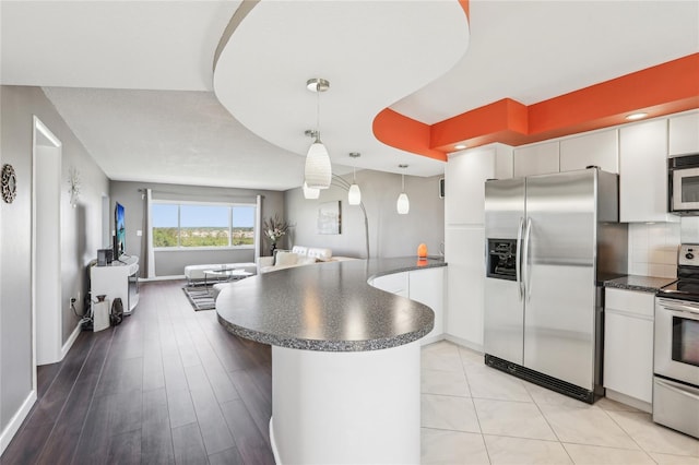 4725 Cove Cir Unit 604, Saint Petersburg, FL 33708 - kitchen with stainless steel appliances, dark countertops, a peninsula, open floor plan, and white cabinetry