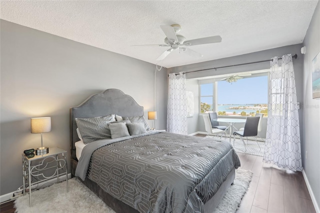 4725 Cove Cir Unit 604, Saint Petersburg, FL 33708 - bedroom with a textured ceiling, baseboards, wood finished floors, and a ceiling fan