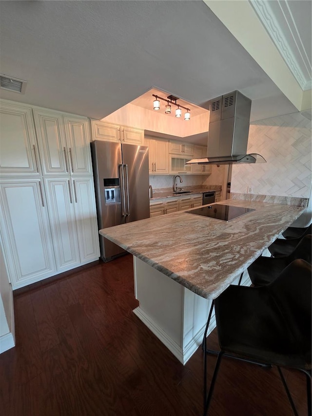 kitchen featuring visible vents, a peninsula, island range hood, black electric cooktop, and high end refrigerator