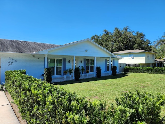 view of front of property with a porch, a front yard, and brick siding
