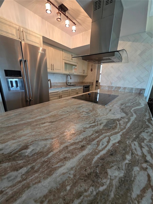kitchen with high end fridge, black electric stovetop, a sink, a raised ceiling, and island exhaust hood