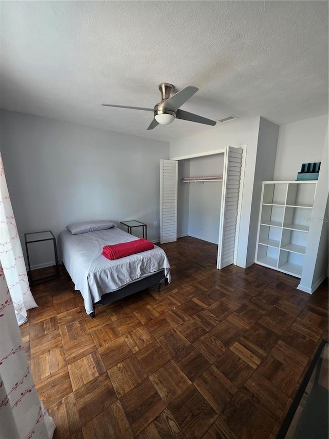 bedroom featuring a ceiling fan, a closet, a textured ceiling, and visible vents