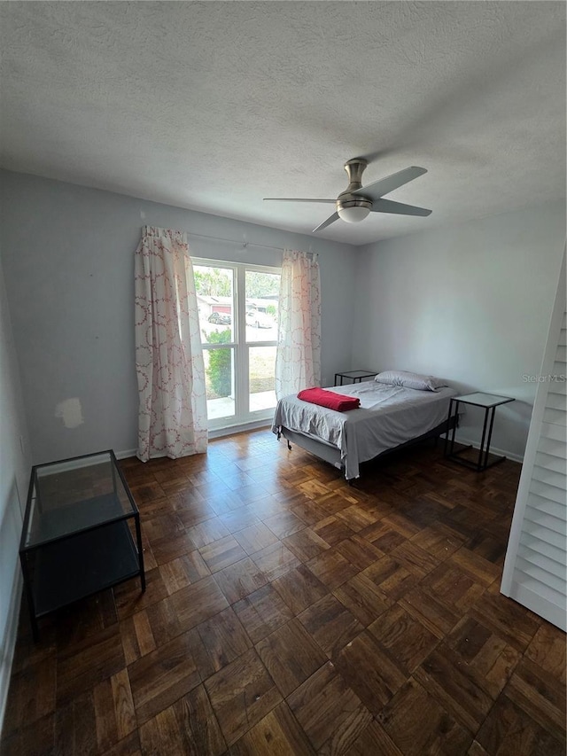 bedroom featuring a textured ceiling, ceiling fan, and baseboards