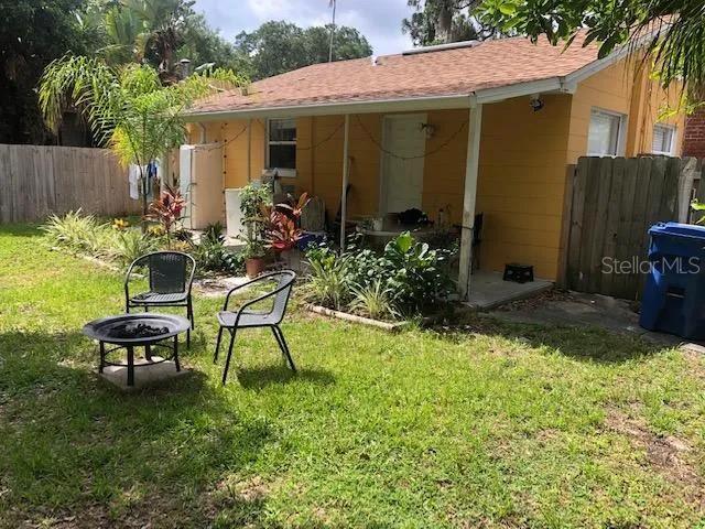 rear view of house with a fire pit, fence, and a lawn