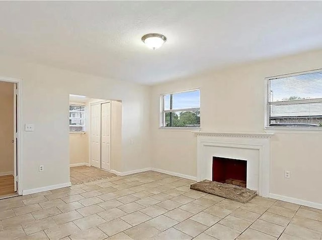 unfurnished living room with baseboards and a fireplace