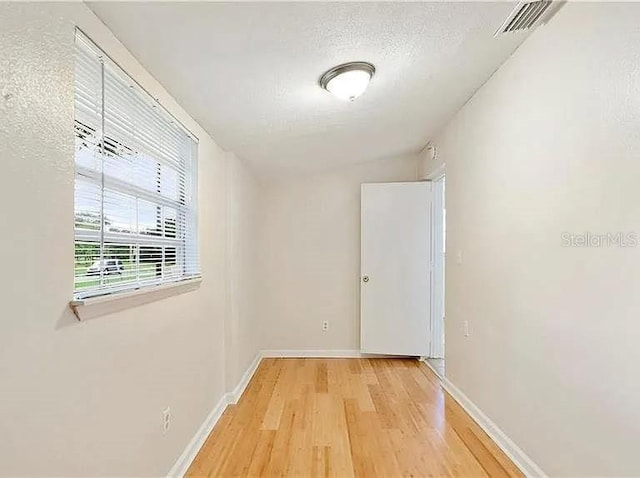 corridor featuring baseboards, visible vents, and light wood-style flooring