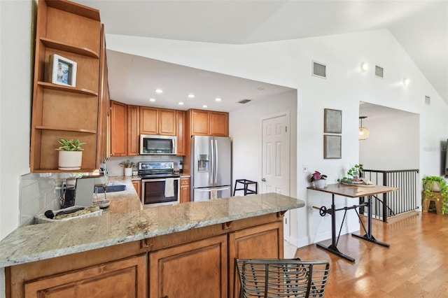 1735 Maryland Ave NE, Saint Petersburg, FL 33703 - kitchen with appliances with stainless steel finishes, open shelves, a peninsula, light stone counters, and brown cabinets